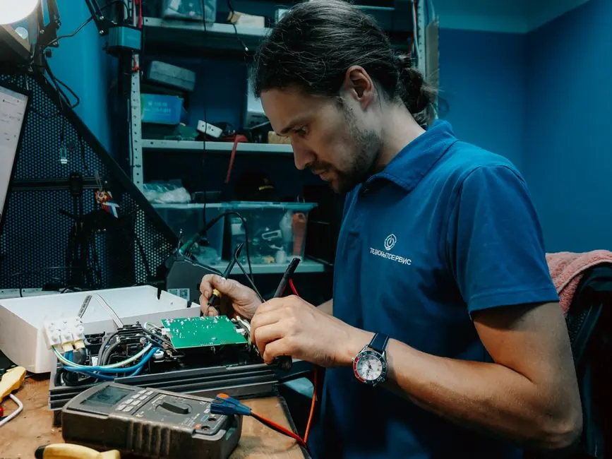 Technician working on a circuit board in a well-equipped workshop, showcasing technical skills and precision.